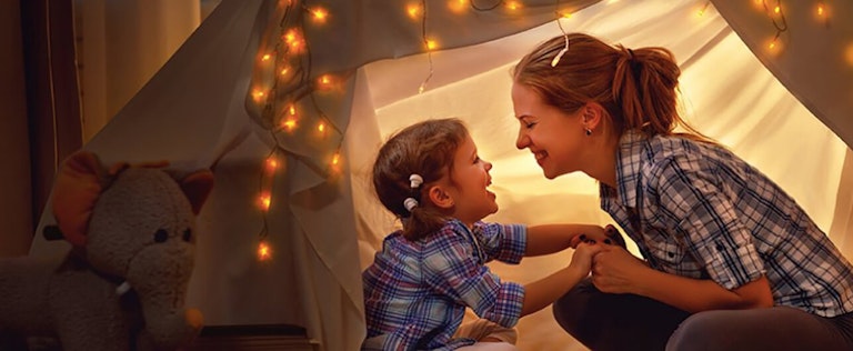 happy mother and daughter in an inside tent fort